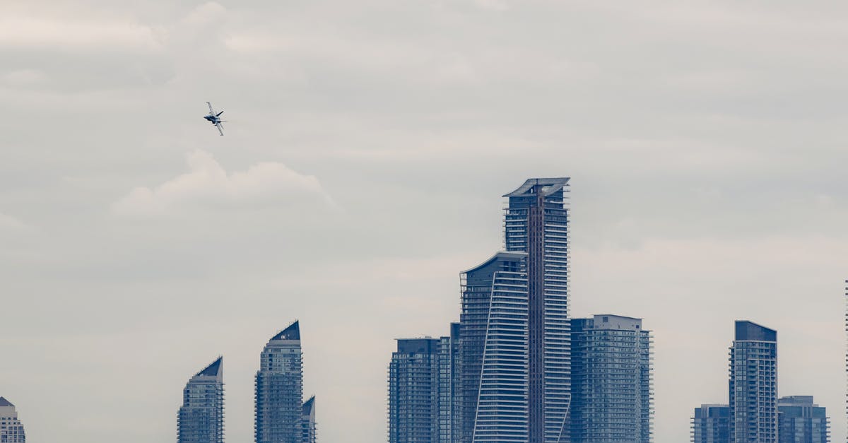 Where can I make complex queries for airplane tickets? - Military airplane flying above modern skyscrapers in city