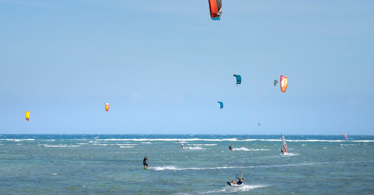 Where can I rent and fly a kite in Singapore? - Unrecognizable travelers practicing different water activities in sea on sunny day