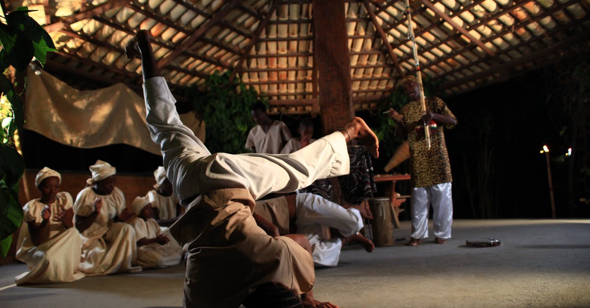 Where can I see folk music and dancing in Moldova? - Full body of African man dancing on head during traditional ceremony in village