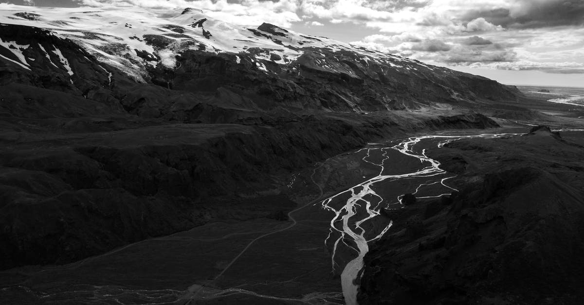 Where can I see volcanic rivers in Iceland? - Dramatic sky over snowy hills in mountainous valley