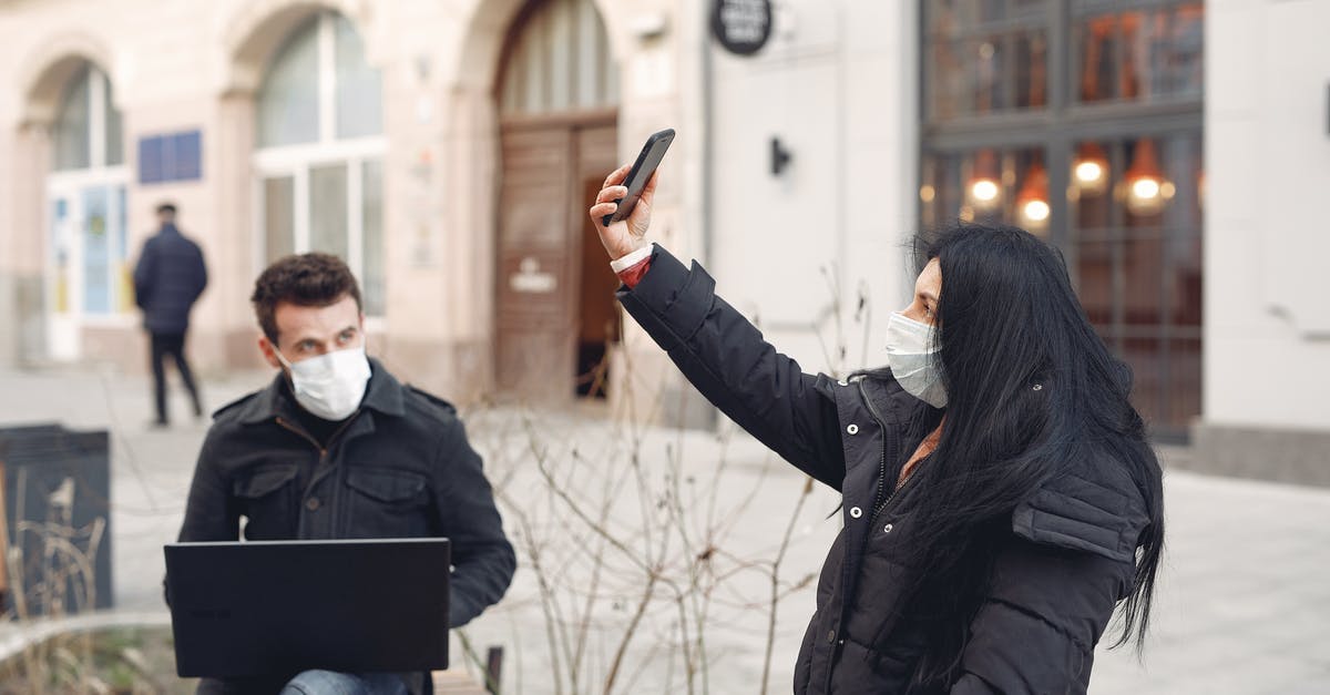 Where can I take a selfie with kangaroos in Australia? - Young couple wearing medical masks using laptop and smartphone on city street