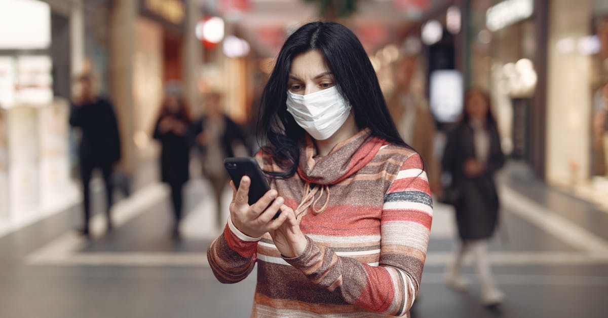 Where can I take a selfie with kangaroos in Australia? - Young female customer in striped wear and protection mask on face using smartphone while standing in shopping mall during coronavirus pandemic