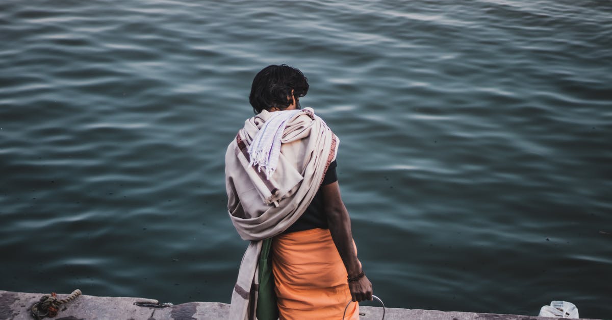 Where can I try a locally brewed Porter in London? - Back view of anonymous ethnic male with metal can standing on wet concrete embankment near rippling sea in coastal area