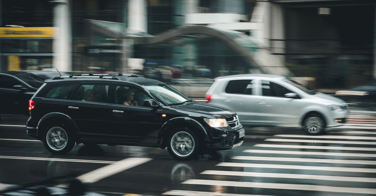 Where do passengers of refuelling stay? - Black Suv Beside Grey Auv Crossing the Pedestrian Line during Daytime