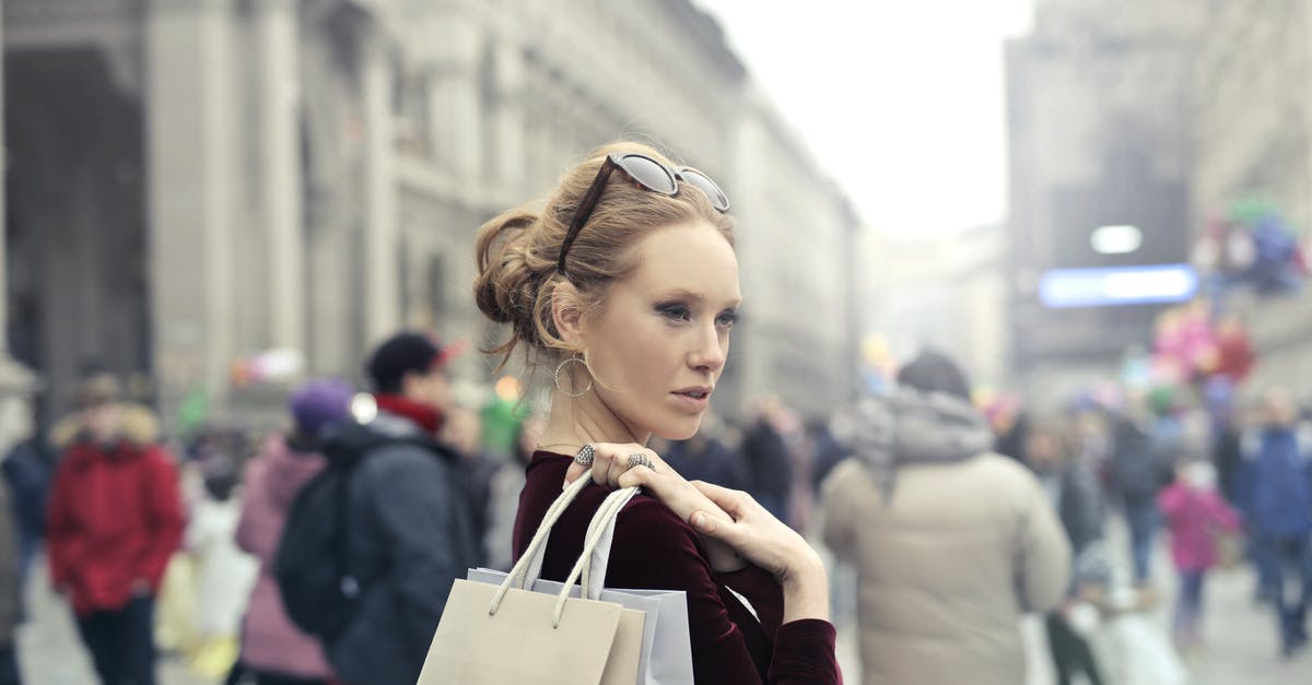 Where do you buy moleskin in Italy? - Woman Wearing Maroon Long-sleeved Top Carrying Brown and White Paper Bags in Selective Focus Photography