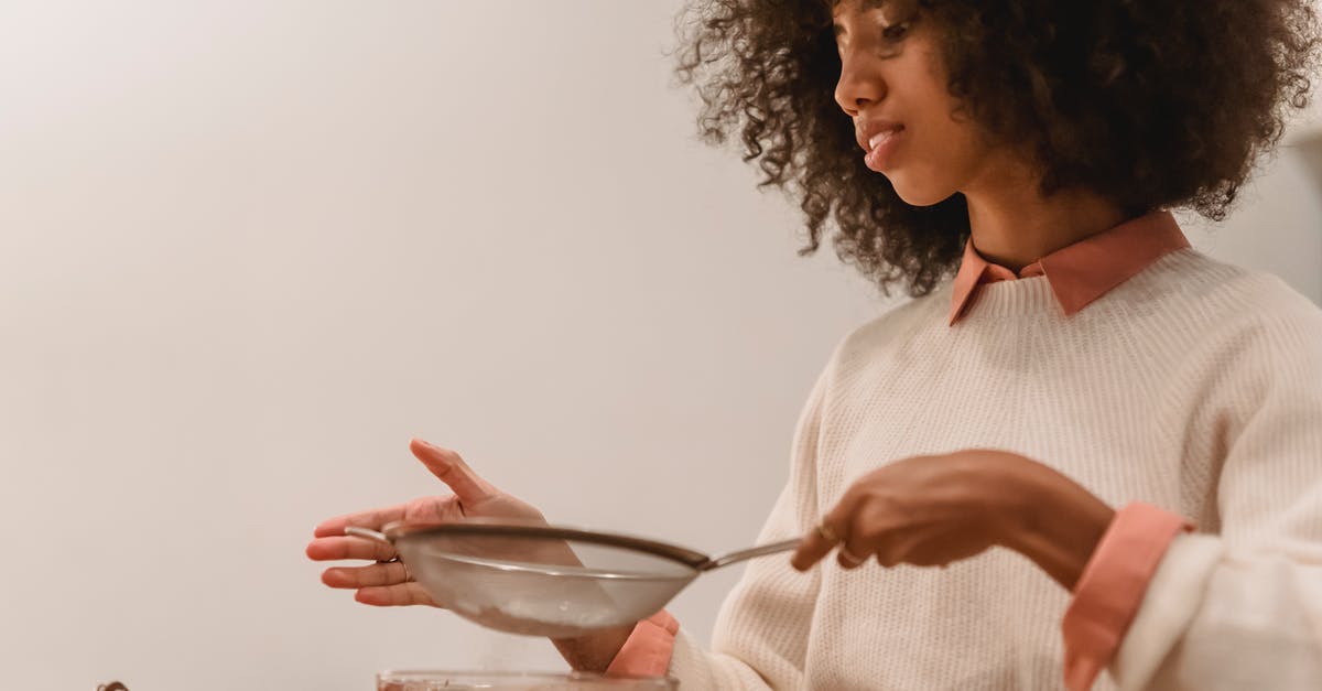 Where I can make chocolates in Switzerland - Side view of African American female cook with sieve pouring flour into bowl with chocolate batter while cooking in kitchen