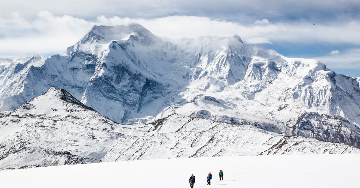 Where in England can I walk on a high tension grid? - Unrecognizable people walking near mountain on snowy terrain