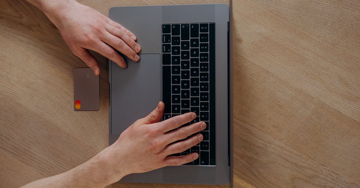 Where in Hong Kong can I purchase an Octopus card? - A Person Using a Laptop Beside a Credit Card on a Wooden Table