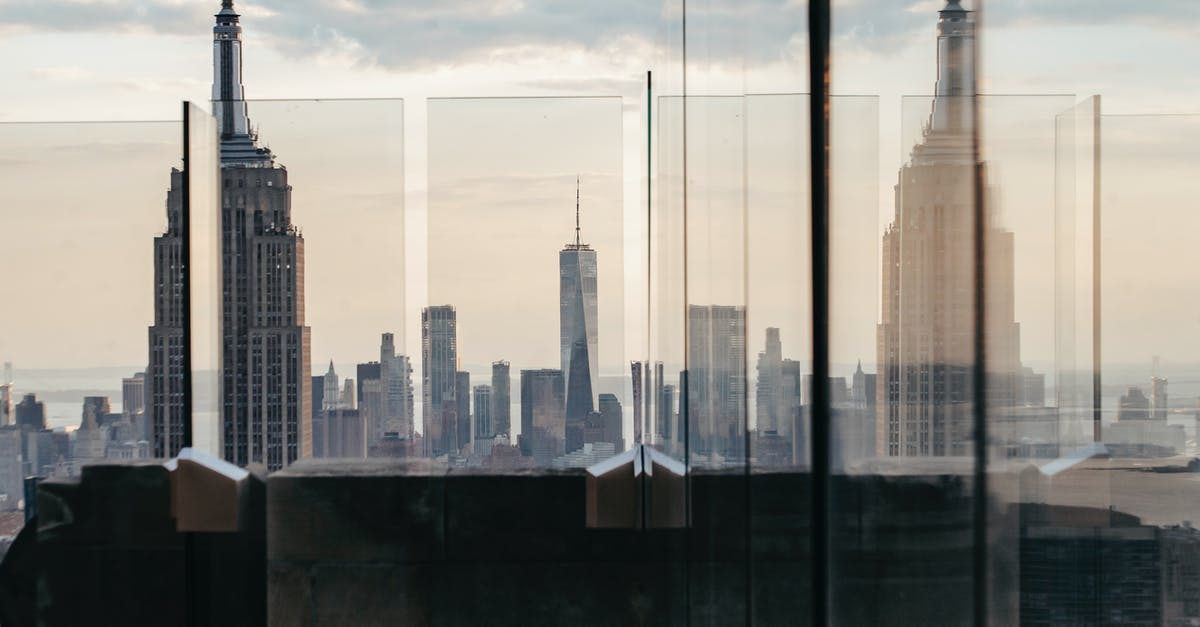 Where is the Hanuatu Island complex? - Through fenced rooftop view of skyscraper facade under cloudy sky in New York City