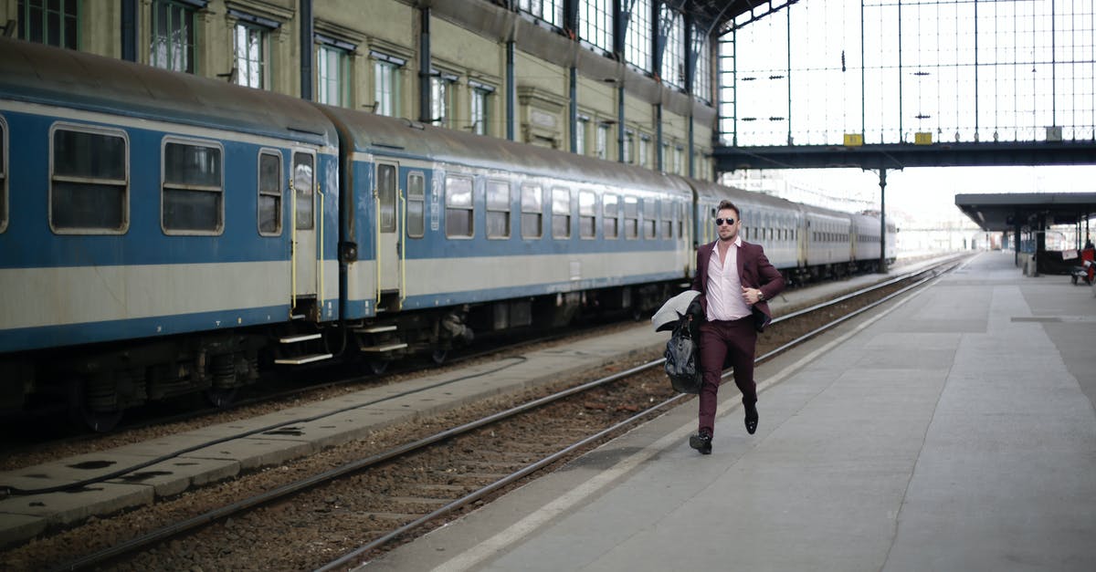 Where is the official Iranian Railways website? - Man in a Purple Suit Running Beside Blue and White Train