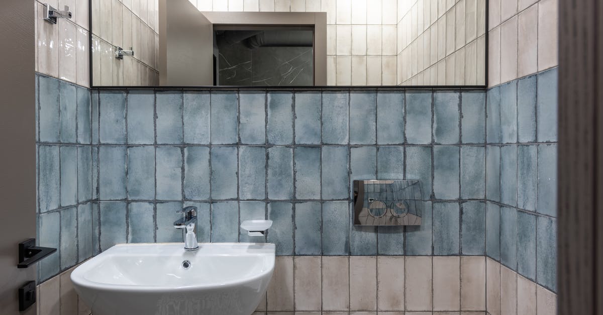 Where is this blue tile in the New York subway? - Interior of modern restroom with ceramic white sink and mirror hanging on white and blue tiled wall