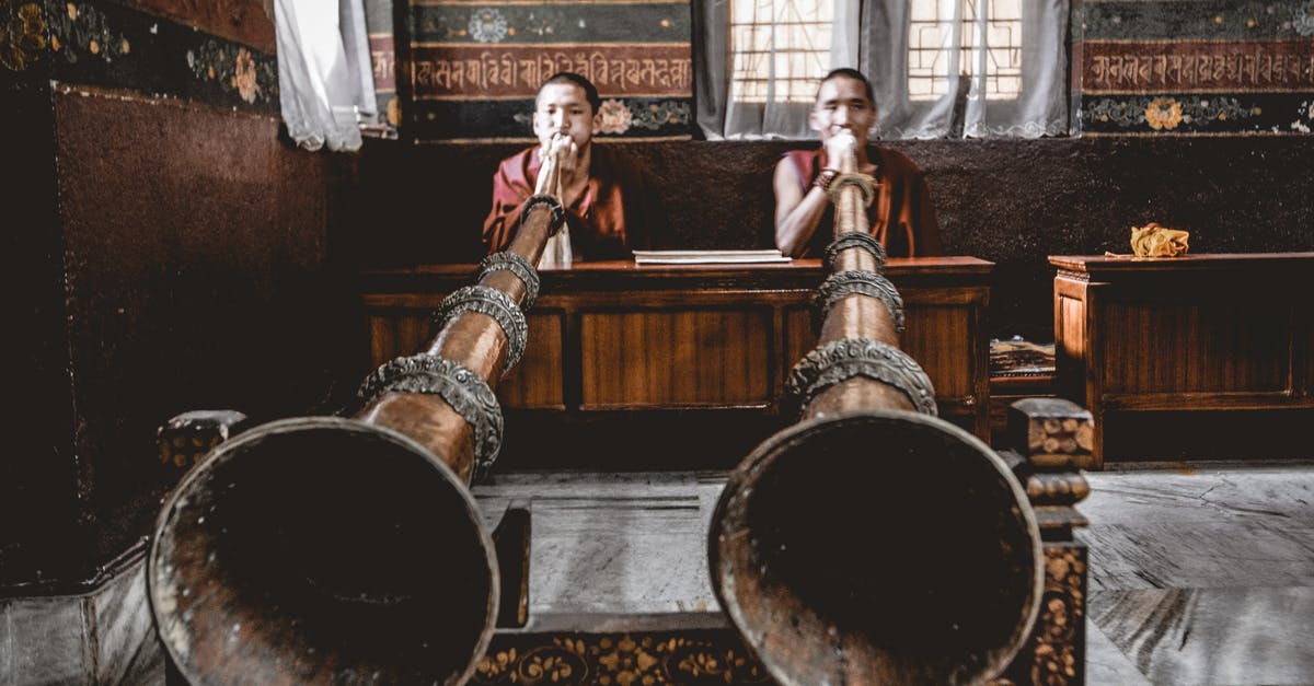 Where is this huge indoor waterfall? - Man Tibetan musicians playing dungchen instrument in temple