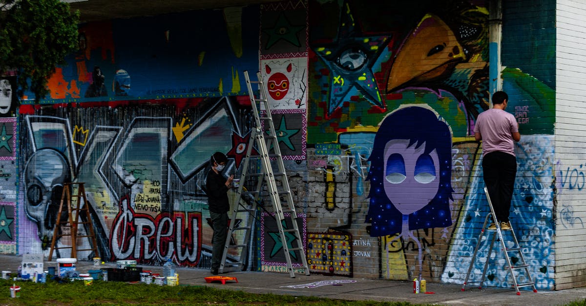 Where is this mural? - Man in Black Shirt Standing Beside Purple and Yellow Graffiti