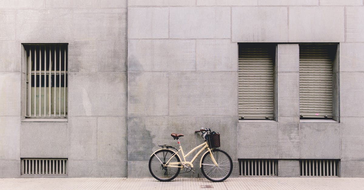 Where is this street-art in Buenos Aires? - Bicycle with basket near handlebar parked against gray concrete building wall on paved sidewalk during daytime