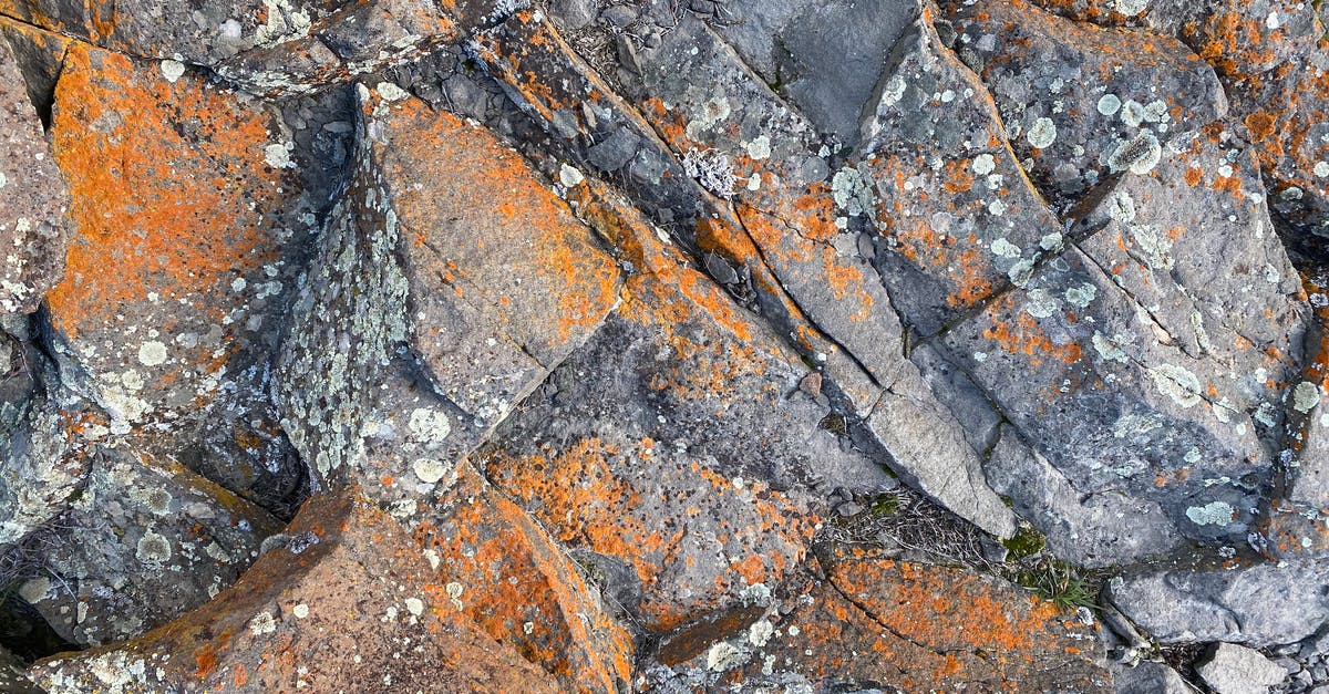 Where on Earth is this manor-house-looking structure? - Top view of rough natural rock surface with cracks and orange rust as abstract  background