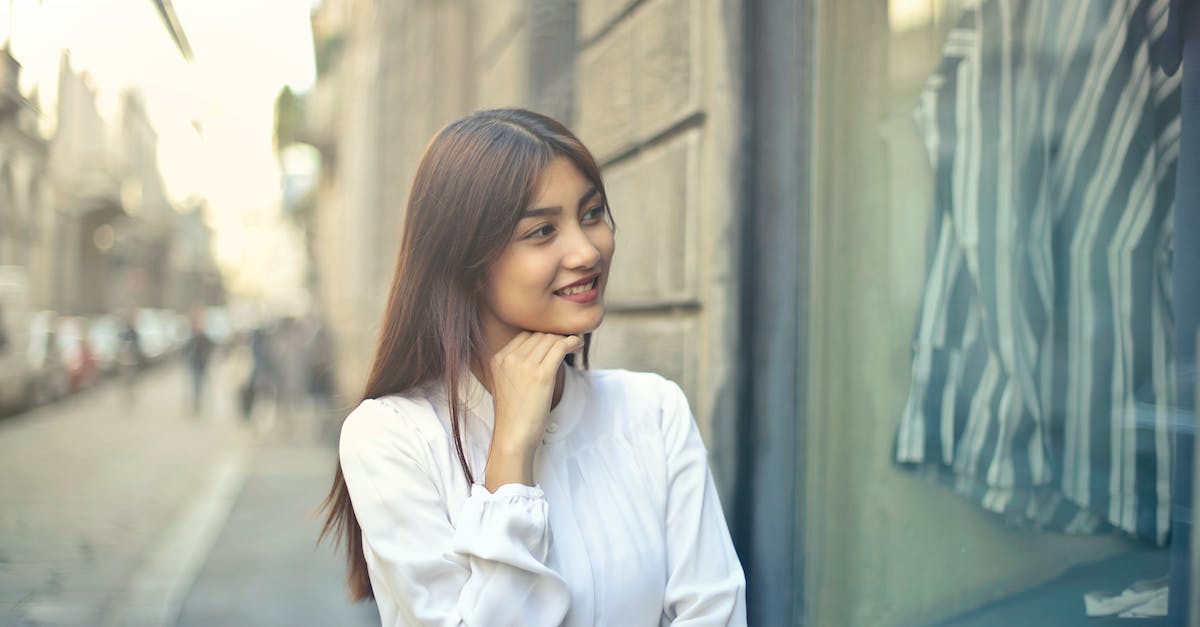 Where should I look for cheap renting cars in USA? - Focus Photo of Woman in White Long-sleeved Dress Standing at the Front of Gray Building