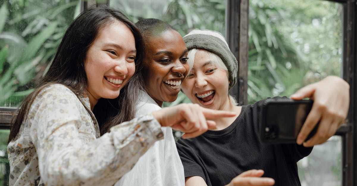 Where should I take visa photo for Italy? - Cheerful diverse female friends laughing at just taken selfie