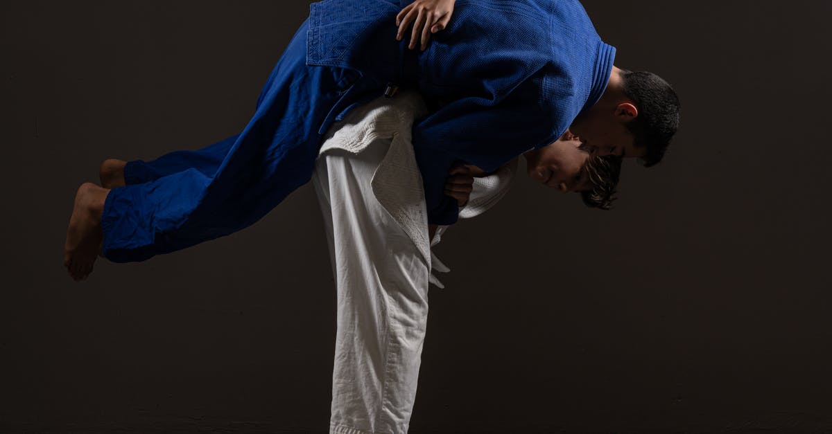 Where to buy a judo uniform (judogi) in Tokyo - Side view of young barefooted Asian male judokas in uniform fighting on floor against black background