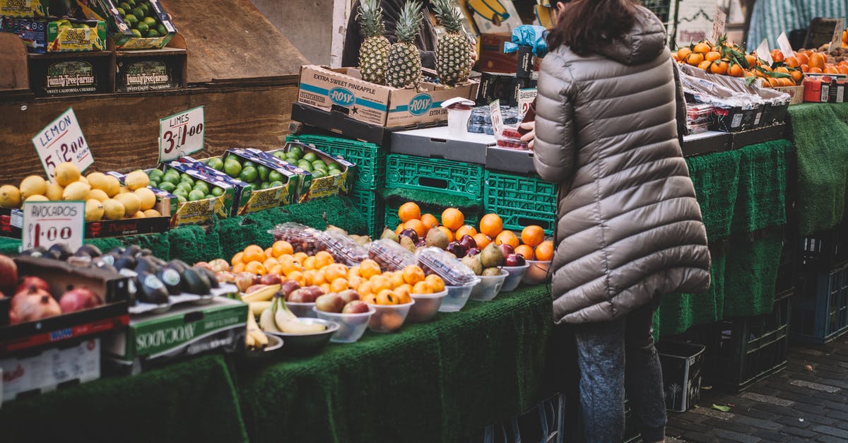 Where to buy cigarettes? At the airport duty free or in local supermarket? - Woman Standing in Front of Assorted Fruits Displayed Where to buy cigarettes? At the airport duty free or in local supermarket? - Woman Standing in Front of Assorted Fruits Displayed