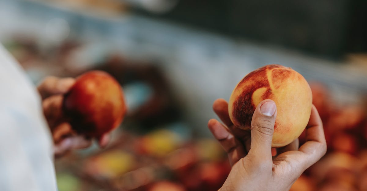 Where to buy cigarettes? At the airport duty free or in local supermarket? - Crop faceless male choosing peaches in food market Where to buy cigarettes? At the airport duty free or in local supermarket? - Crop faceless male choosing peaches in food market