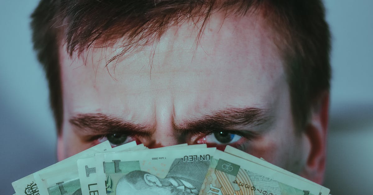 Where to hide your money in high-risk areas? - Serious young male covering face with banknotes