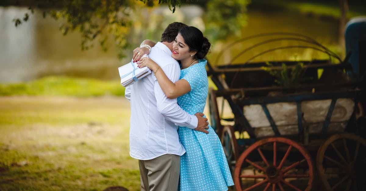 Where to meet outside Heathrow T3? - Cheerful ethnic lady in summer dress with stack of letters in hand tenderly embracing faceless boyfriend after long separation standing in green rural backyard