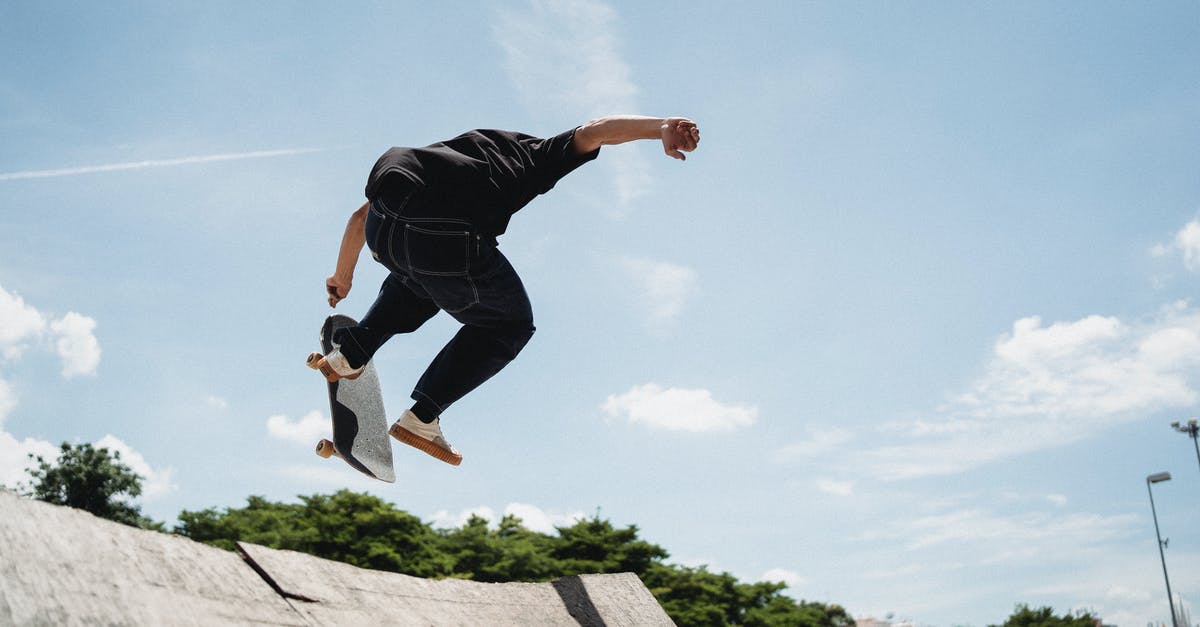 Where to practice violin 5 hours every day in Paris? - Back view of anonymous young guy performing high ollie stunt on old ramp in park in city on sunny summer day