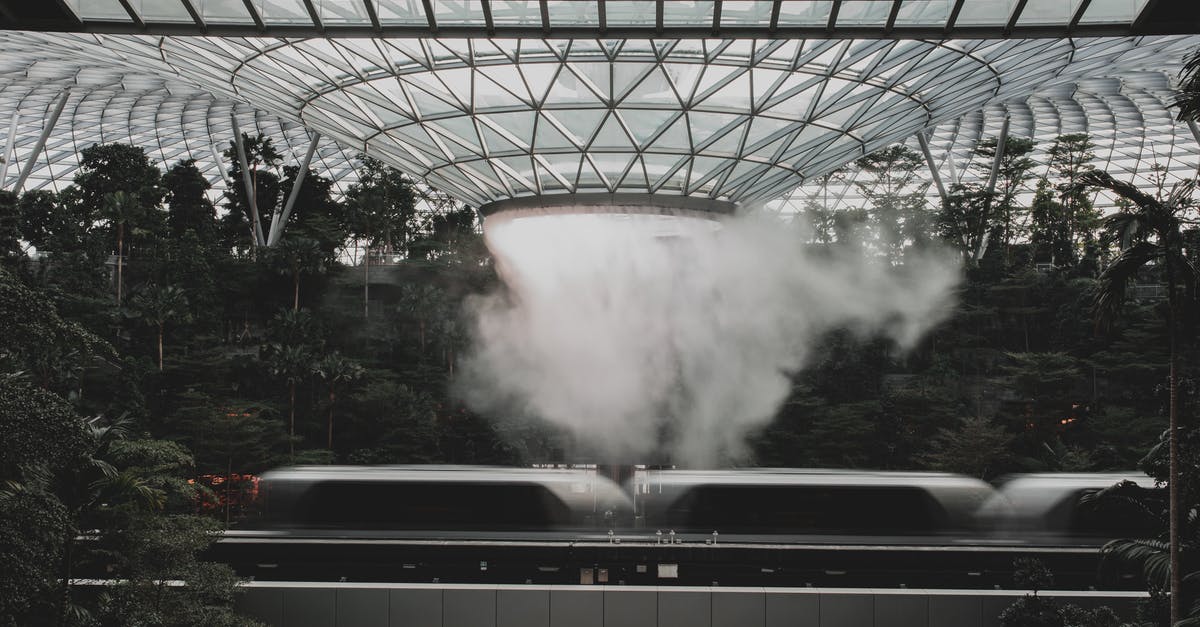 Where to shower for free in Singapore airport? - Modern train riding under indoors waterfall in modern airport