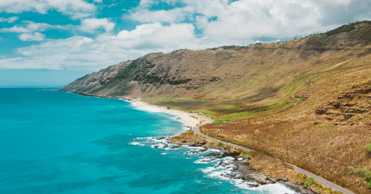 Where was this picture of a seaside road taken? - Seaside Road Along Mountain Range Under Blue Sky