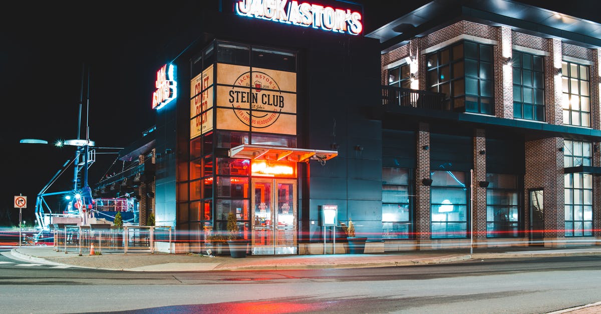 Which AA Admirals' Club location at DFW is most comfortable? - Exterior of modern building with glass facade and illuminated signboard located near asphalt roadway at night