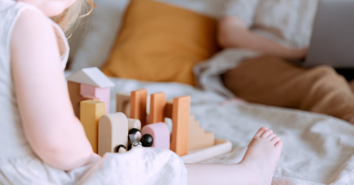 Which airlines ban the use of Knee Defenders during flight? - Anonymous toddler girl playing with wooden blocks on bed while mother using laptop