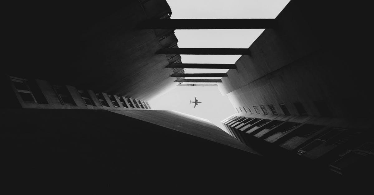 Which airplane is the safest? - Airplane Flying Between Skyscrapers in Grayscale