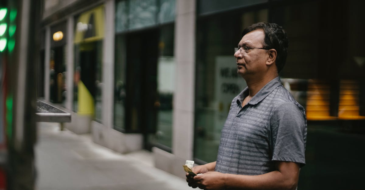 Which ATMs offer no-fee cash withdrawals in Chile? - Serious ethnic man standing with money on street