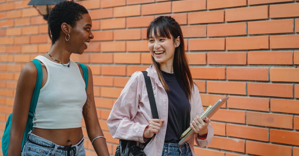Which brand of backpack should I carry so as to not stick out in Europe? - Cheerful multiracial female students wearing casual clothes carrying backpack and notebooks near college brick wall while discussing plans and looking at each other with smiles Which brand of backpack should I carry so as to not stick out in Europe? - Cheerful multiracial female students wearing casual clothes carrying backpack and notebooks near college brick wall while discussing plans and looking at each other with smiles
