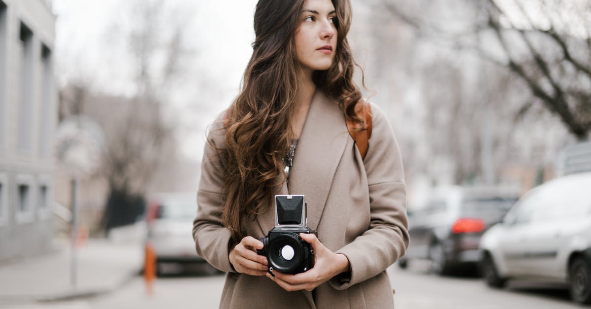 Which city is shown in the film "A trip to Wiesbaden"? - Concentrated young female traveler in stylish coat taking pictures on vintage film camera during sightseeing in city