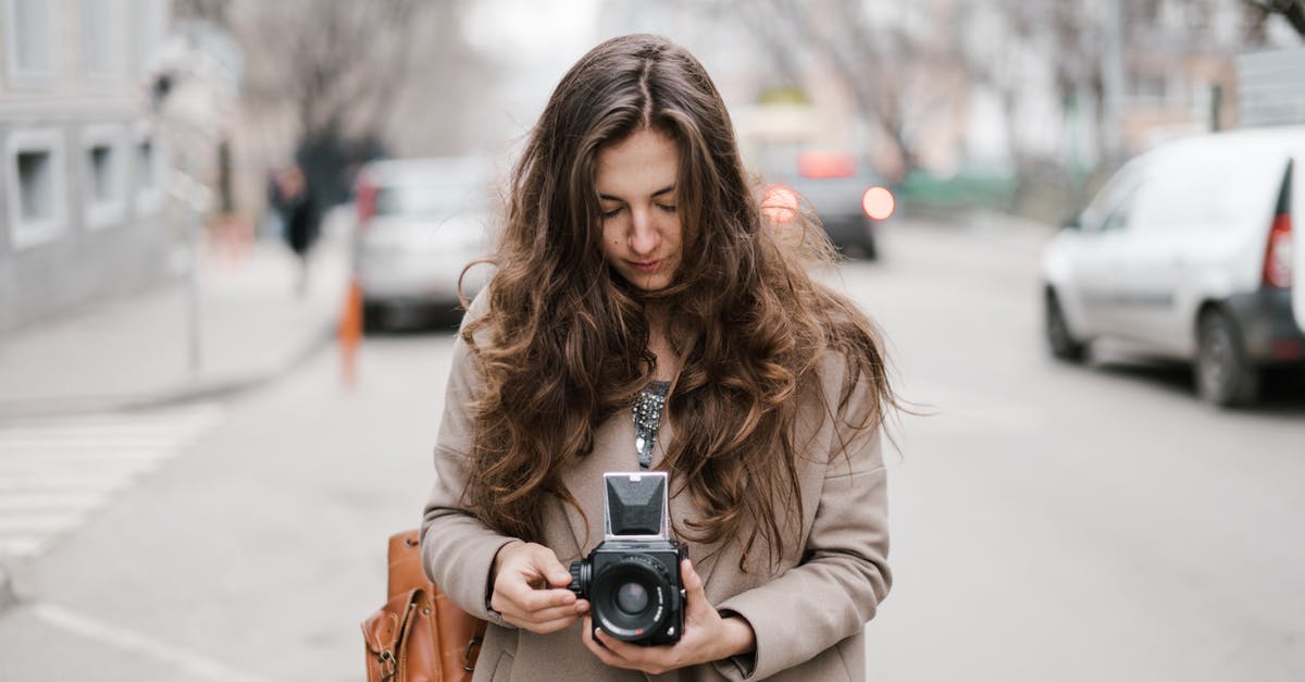 Which city is shown in the film "A trip to Wiesbaden"? - Young pensive female with long hair in casual outfit walking on street and setting up retro camera