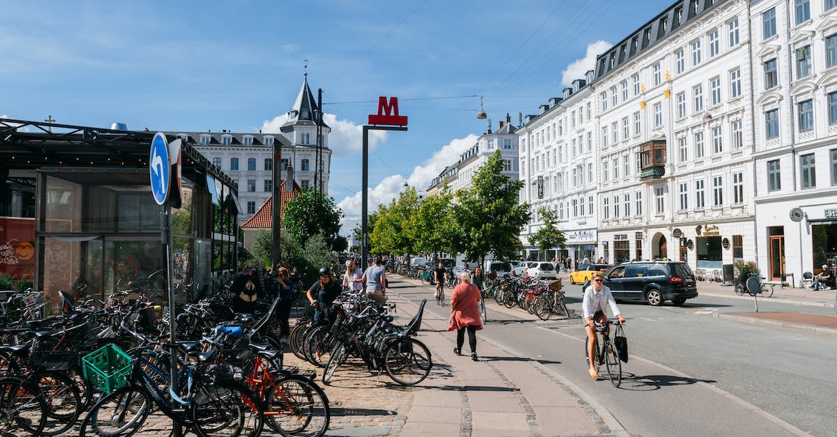 Which European cities have bike rental stations for tourists? - People Walking on Sidewalk Near White Concrete Building