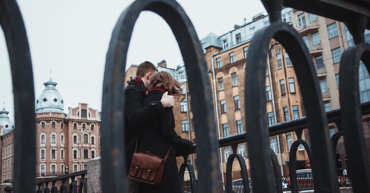 Which I-94 date do I believe? - From below of anonymous female and male in warm clothes standing near railing together and hugging in cold weather