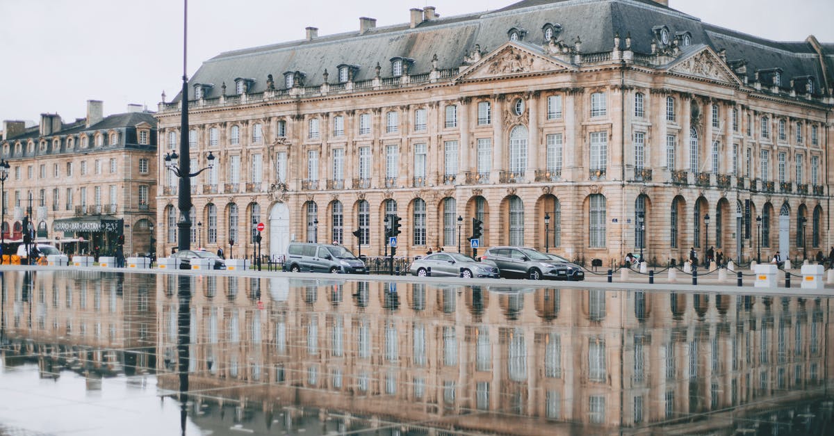 Which scenic road to take to the south of France? - Square with Garonne river and aged house facades near road with cars in Bordeaux