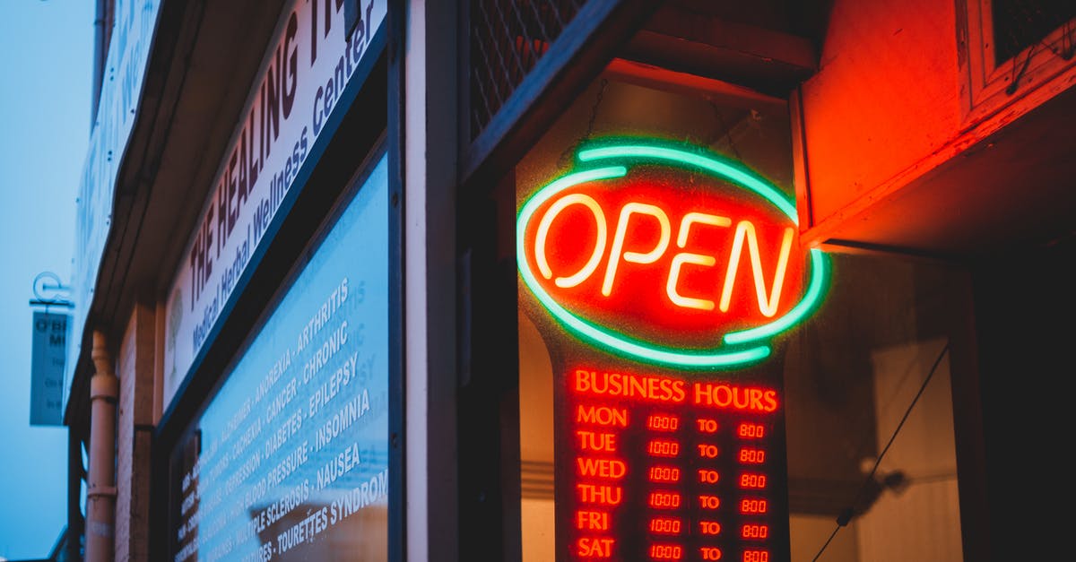 Which sights are open late in Paris? - Colorful glowing neon signboard with word open and timetable on urban avenue in late evening