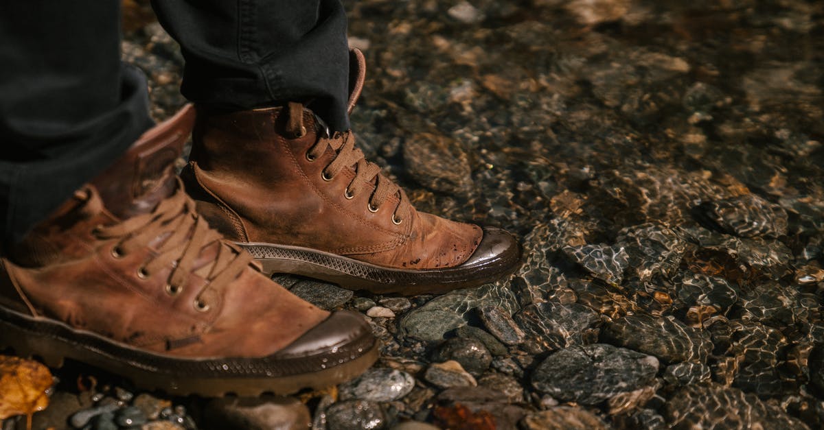 Which trekking shoes to get for trekking in Costa Rica - Crop unrecognizable person in autumn boots and black jeans standing near water in forest