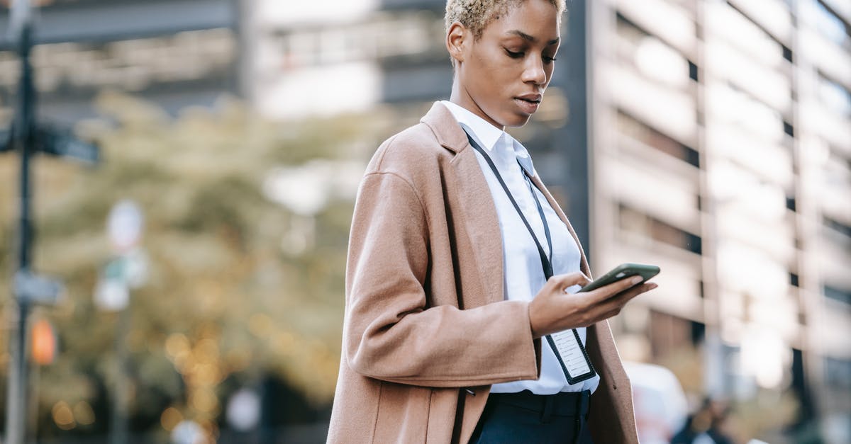 Who is officially responsible for rebooking a missed connection? - Focused black businesswoman browsing smartphone on urban street