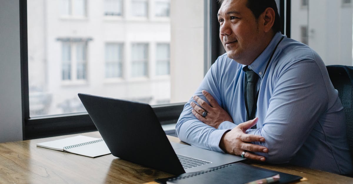 Who is officially responsible for rebooking a missed connection? - Adult successful ethnic male boss wearing shirt and tie sitting with hands crossed at workplace with documents and netbook