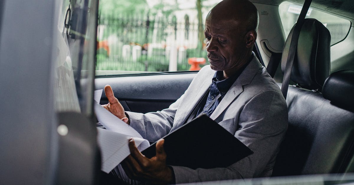 Who is responsible for the check-in queues? - Focused black responsible man working with papers in car