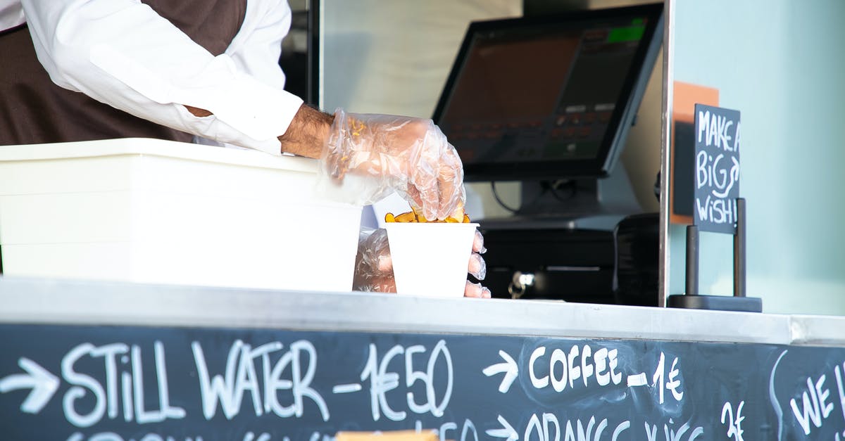 Why are airline meal portions so small? - Low angle of crop anonymous male seller with cup of fried food at counter with cashier