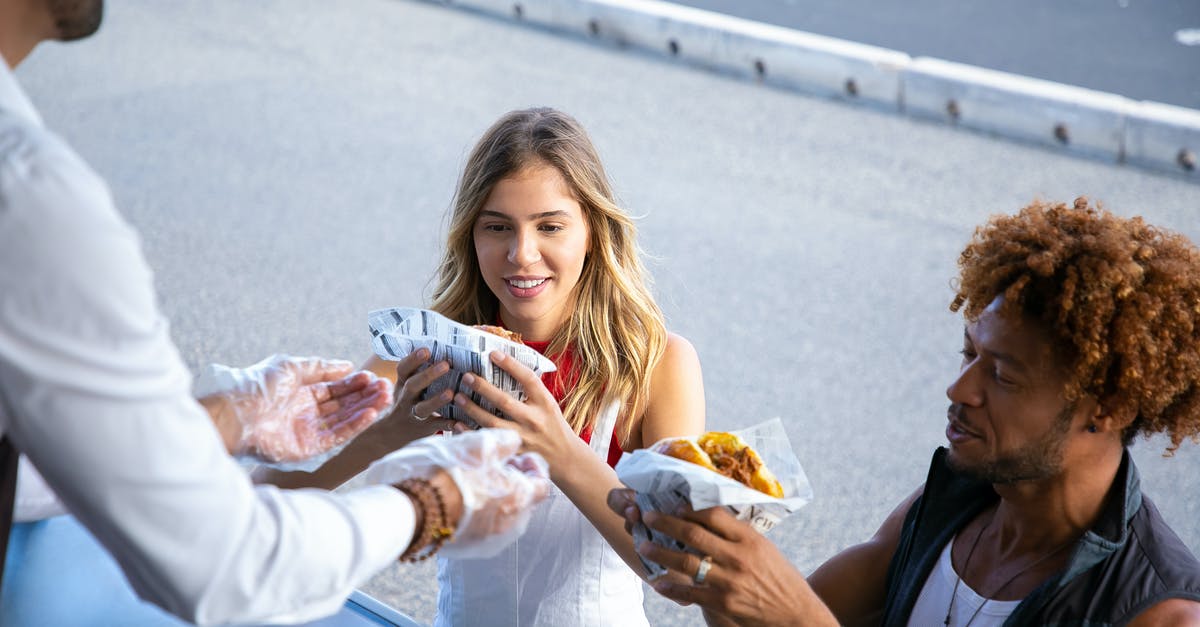 Why are airline meal portions so small? - High angle of positive multiracial couple getting delicious burgers from salesman working in food truck