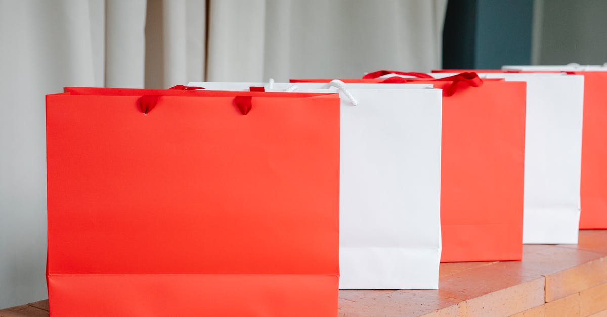 Why are so many airline check-in counters idle so often? - Set of red and white paper shopping bags placed on brick shelf in studio