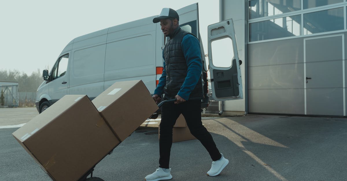 Why are there no courier services or box-rentals near airport security? - Man in Blue and Red Plaid Dress Shirt and Black Pants Standing Beside Brown Cardboard Box Why are there no courier services or box-rentals near airport security? - Man in Blue and Red Plaid Dress Shirt and Black Pants Standing Beside Brown Cardboard Box