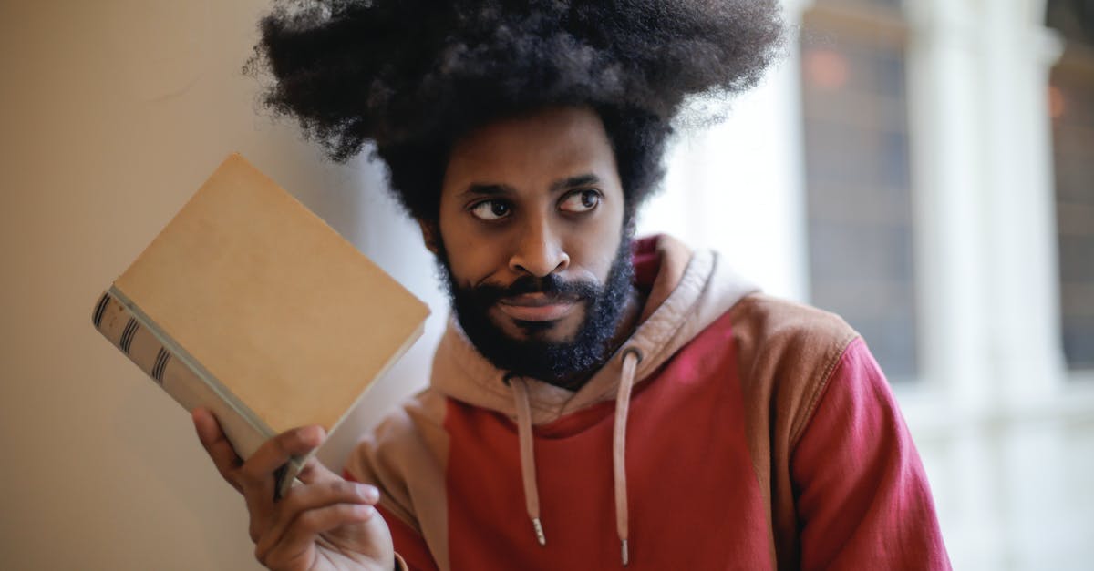 Why booking services never consider MIA for transfers? - Young bearded ethnic male student with creative Afro hairstyle wearing hoodie sweatshirt looking away with doubt expression while taking old book against blurred exterior of aged university