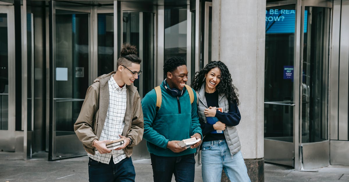 Why can't I book this multi-city fare on American Airlines? - Young cheerful multiethnic students with books having fun on urban pavement while speaking in daylight